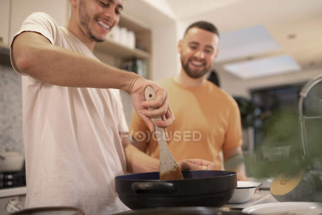 Happy gay male couple cooking in kitchen — Stock Photo