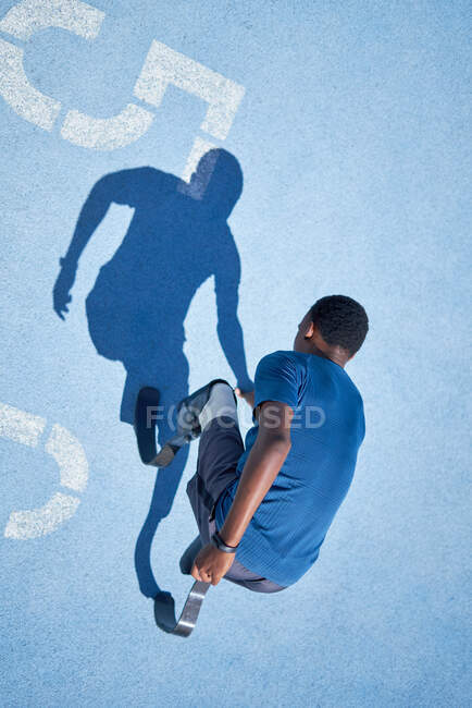 Velocista amputato maschio su pista sportiva blu — Foto stock
