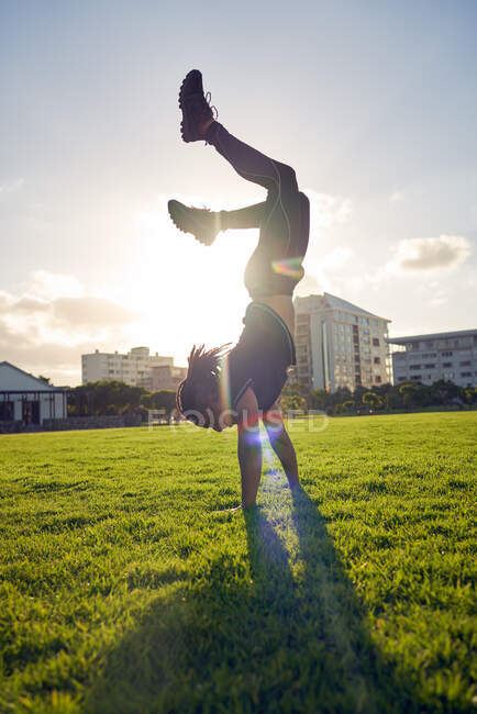 Беззаботный молодой человек делает стойку на руках в солнечном парке — стоковое фото