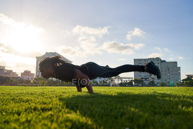 Atlético joven haciendo ejercicio en el soleado parque urbano - foto de stock