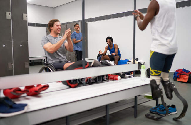 Happy amputee and wheelchair athletes clapping in locker room — Stock Photo