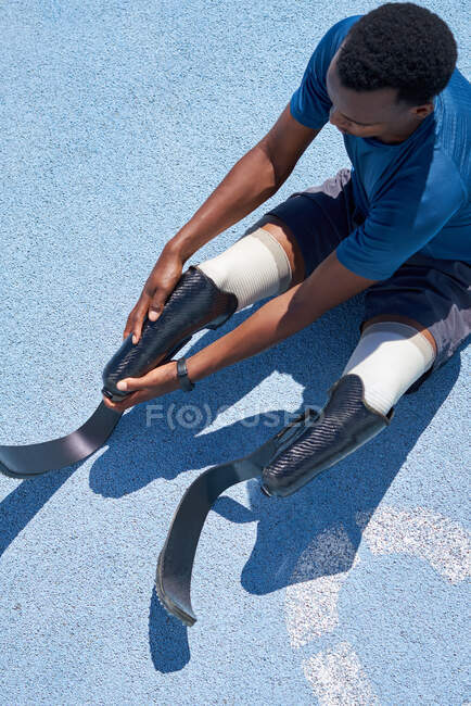 Jeune athlète masculin avec prothèses de lame de course sur piste de sport bleue — Photo de stock