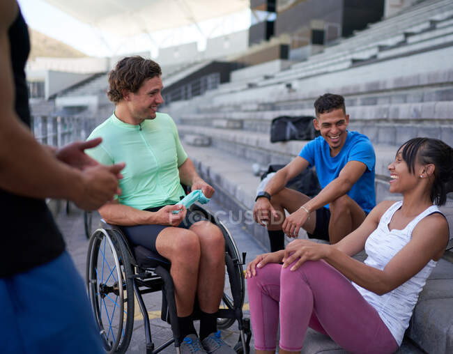 Happy athletes laughing and talking in bleachers — Stock Photo