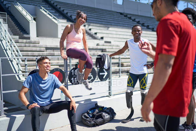 Young athlete friends talking in sunny sports stadium — Stock Photo