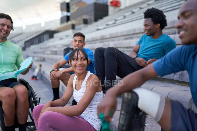 Happy young athlete friends in bleachers — Stock Photo