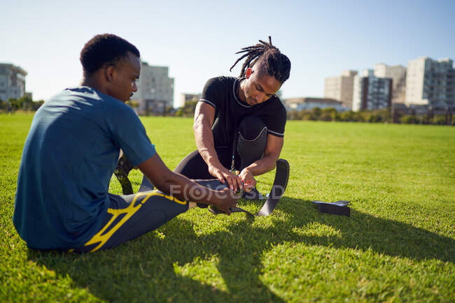 Coach helping young male amputee athlete with running blade prosthetic — Stock Photo