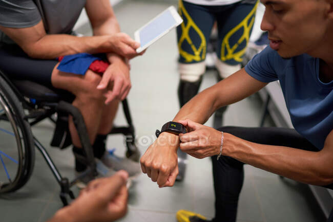 Male amputee and wheelchair athletes with smart phone in locker room — Stock Photo