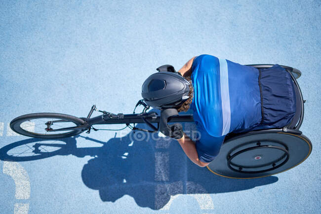 Atleta su sedia a rotelle maschile su soleggiata pista sportiva blu — Foto stock