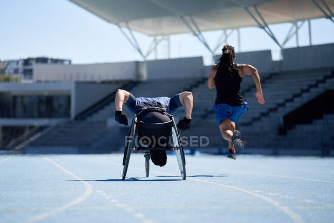 Wheelchair athlete training on sunny blue sports track — Stock Photo