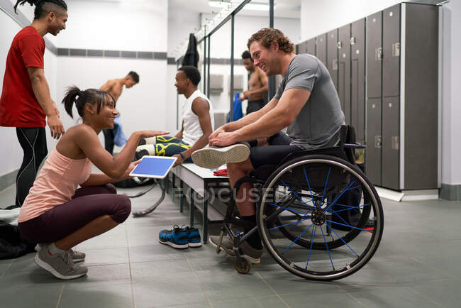 Coach and wheelchair athlete talking in locker room — Stock Photo