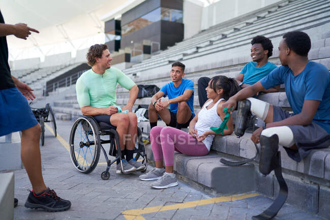 Diverse young athletes talking in stadium bleachers — Stock Photo