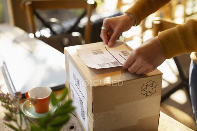 Владелец предприятия помещает этикетку доставки на картонную коробку — стоковое фото