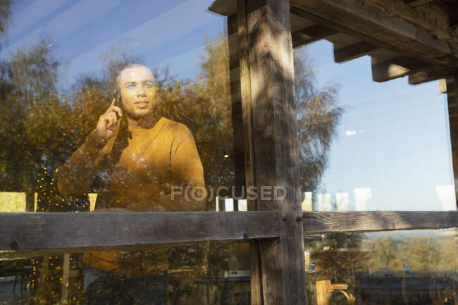 Чоловік розмовляє на смартфоні у сонячному вікні ресторану — стокове фото