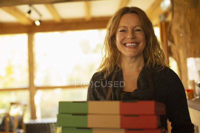 Retrato feliz mujer pizzería propietario con cajas de pizza - foto de stock