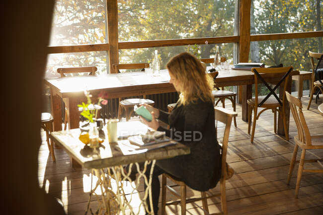 Businesswoman working at sunny cafe table — Stock Photo