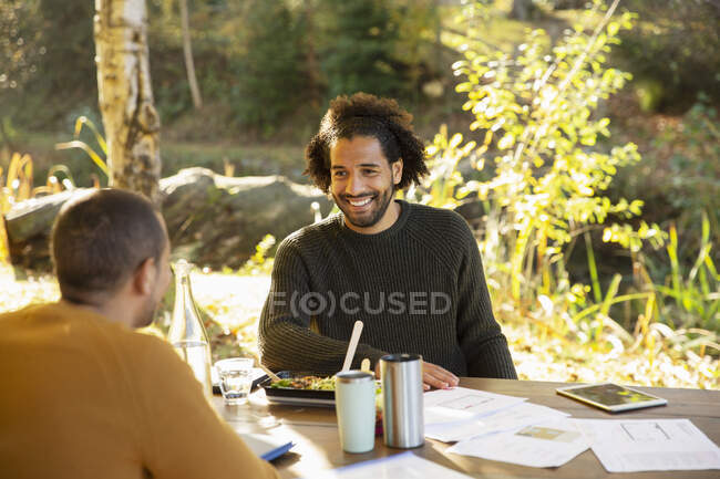 Businessmen eating lunch and discussing paperwork at park table — Stock Photo