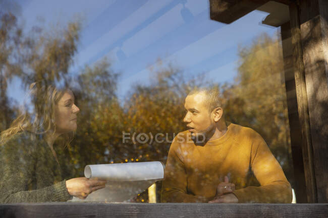 Empresários discutindo papelada na janela do café ensolarado — Fotografia de Stock