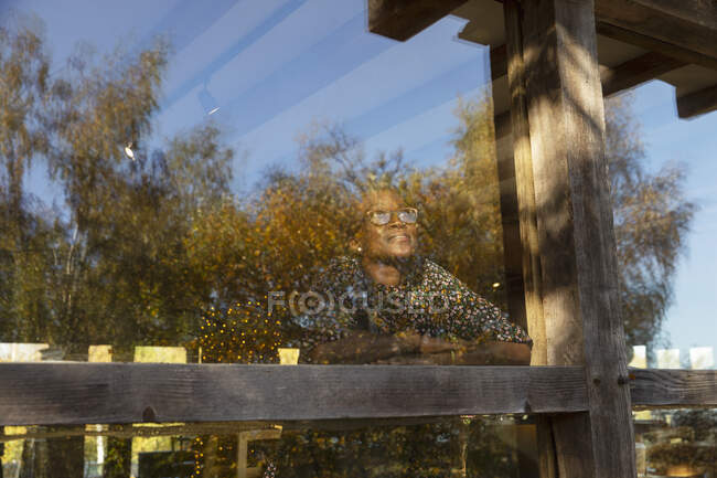 Nachdenkliche Frau blickt aus Restaurantfenster auf Bäume — Stockfoto