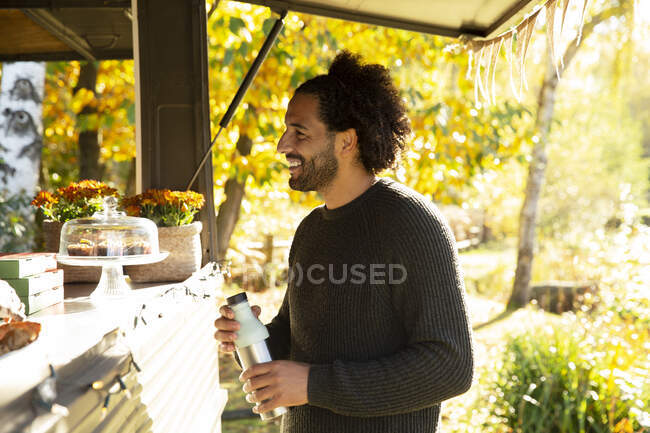 Sorrindo cliente masculino encomendar a partir de caminhão de alimentos no parque de outono — Fotografia de Stock