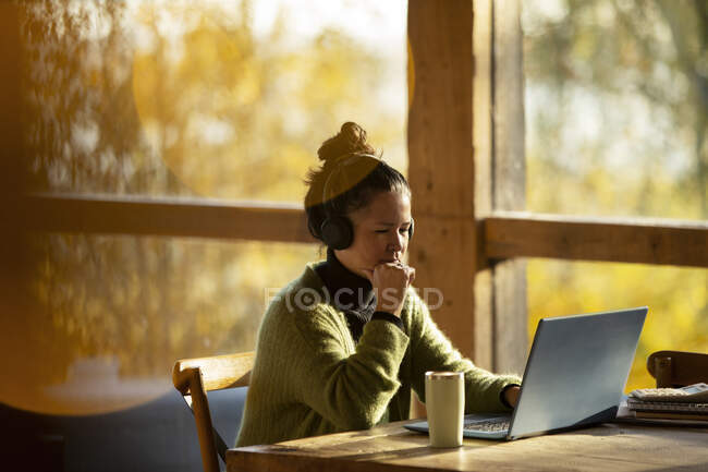 Femme d'affaires avec écouteurs travaillant à un ordinateur portable dans un café — Photo de stock
