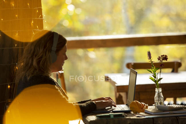 Donna d'affari con cuffie che lavorano al computer portatile in caffè — Foto stock