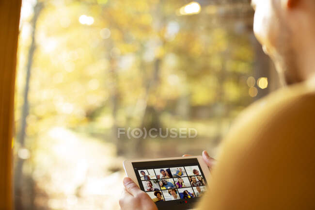 Чоловік спілкується з друзями на цифровому планшеті у сонячному вікні — стокове фото