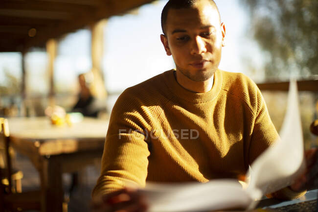 Бизнесмен рассматривает документы в солнечном кафе — стоковое фото