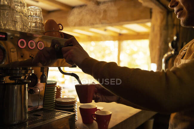Masculino barista preparando cappuccino na máquina de café expresso no café — Fotografia de Stock