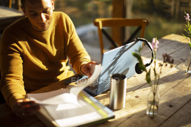 Empresário revisando papelada no laptop no café — Fotografia de Stock