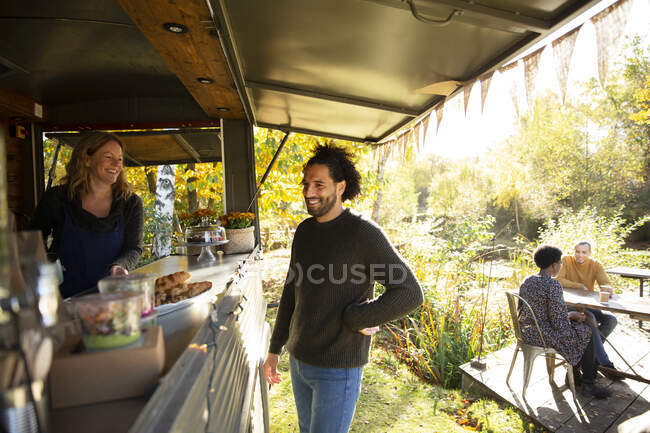 Proprietário do carrinho de alimentos e cliente conversando no parque — Fotografia de Stock