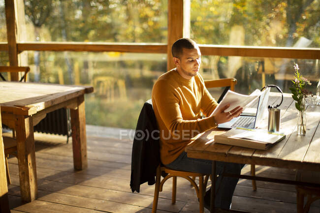 Homme d'affaires avec paperasserie travaillant dans un café ensoleillé d'automne — Photo de stock