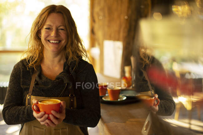 Portrait happy female coffee shop owner with cappuccino — Stock Photo