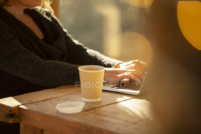 Femme avec café travaillant à l'ordinateur portable sur la table de café — Photo de stock