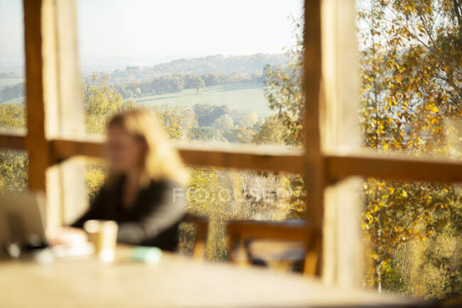 Femme travaillant dans un café avec vue panoramique ensoleillée de l'automne — Photo de stock