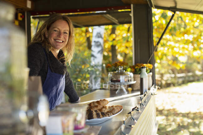 Portrait femme heureuse propriétaire de chariot de nourriture travaillant dans le parc — Photo de stock