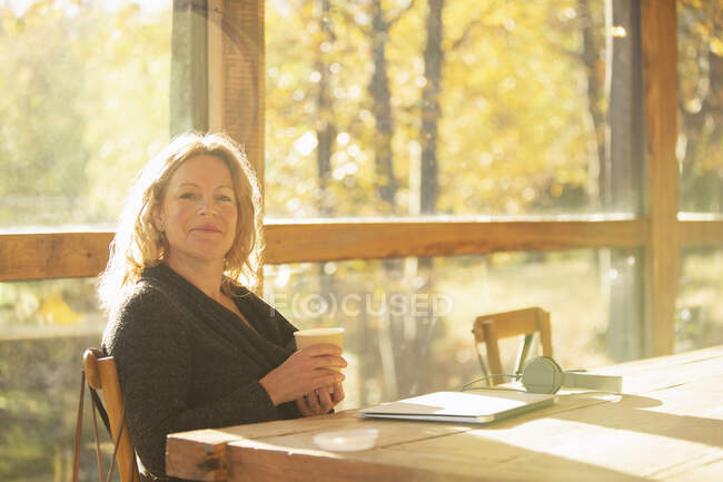 Portrait confident businesswoman with coffee working in autumn cafe — Stock Photo