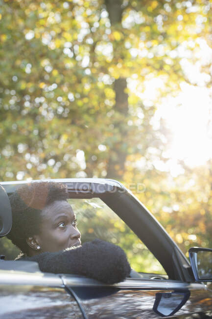 Mujer montando en convertible en el soleado parque de otoño - foto de stock