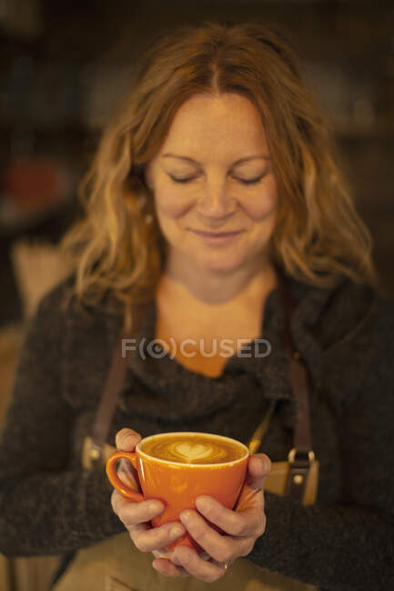 Barista fêmea feliz segurando cappuccino com espuma de forma de coração — Fotografia de Stock