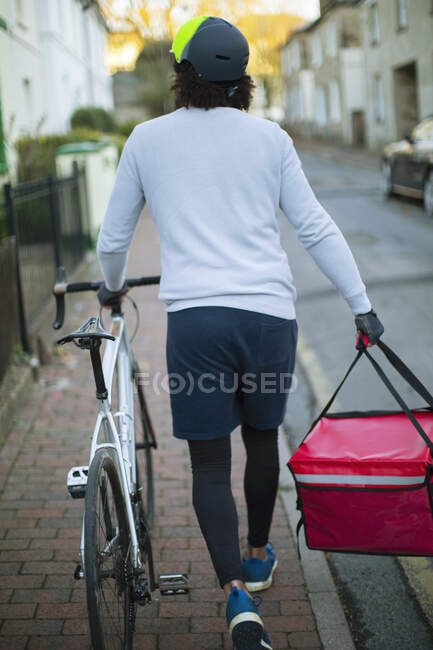 Hombre mensajero de bicicleta entrega de alimentos en el barrio urbano - foto de stock