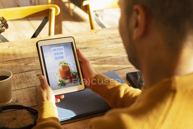 Propietario de restaurante masculino mirando el sitio web de entrega en tableta digital - foto de stock