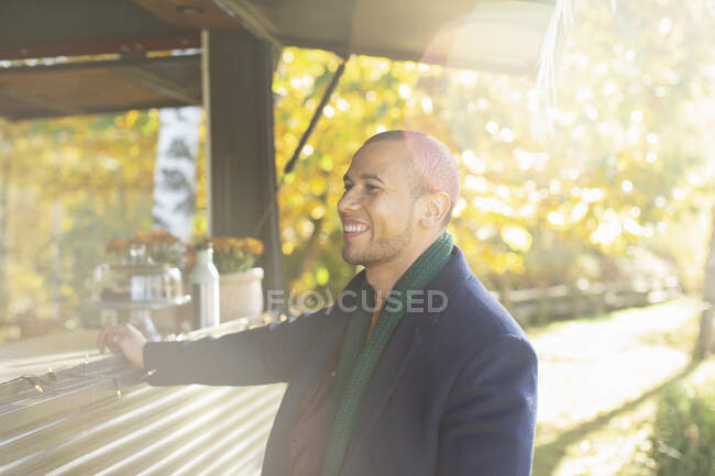 Щасливий чоловік клієнт замовляє їжу в кошику для їжі в сонячному осінньому парку — стокове фото