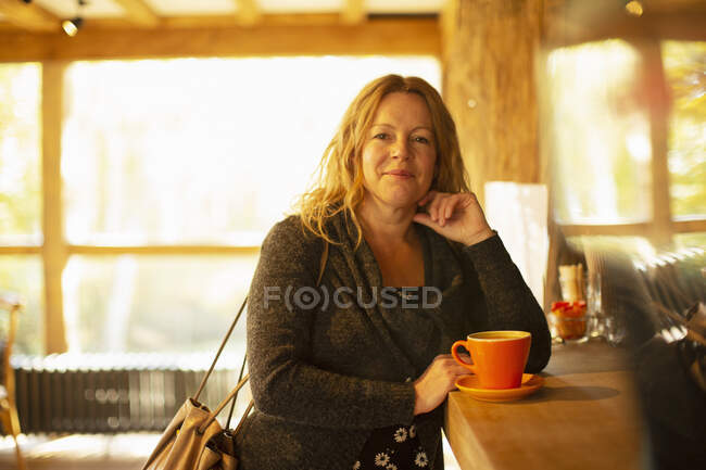 Retrato mujer feliz pidiendo cappuccino en el mostrador de café - foto de stock