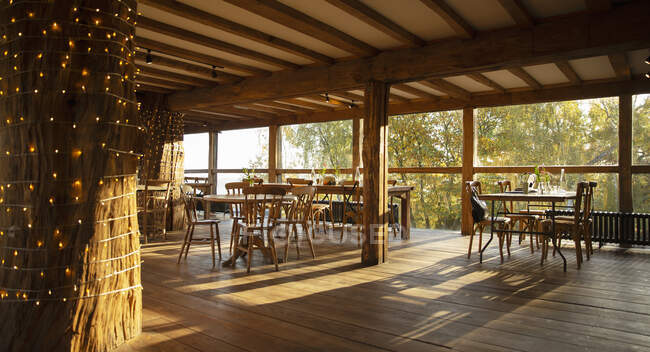 Tavoli e sedie in legno in soleggiato ristorante vuoto — Foto stock