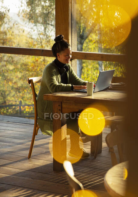 Kleinunternehmer arbeitet im sonnigen Herbstcafé am Laptop — Stockfoto
