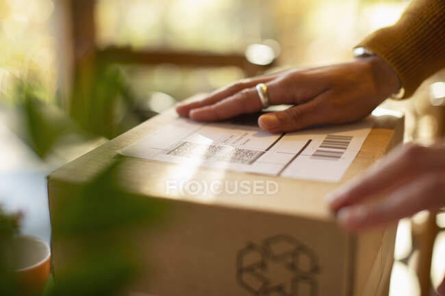 Close up business owner placing shipping label on package — Stock Photo