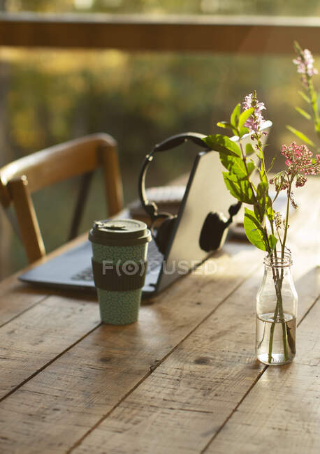 Laptop, Kaffee und einfacher Blumenstrauß auf Cafétisch — Stockfoto