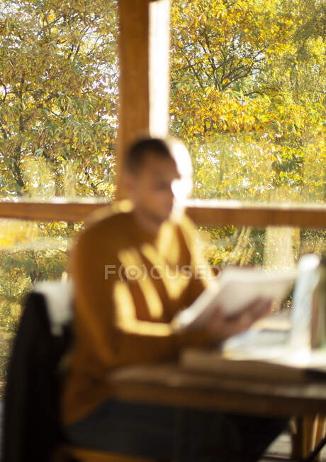 Empresario con papeleo trabajando en soleado café de otoño - foto de stock