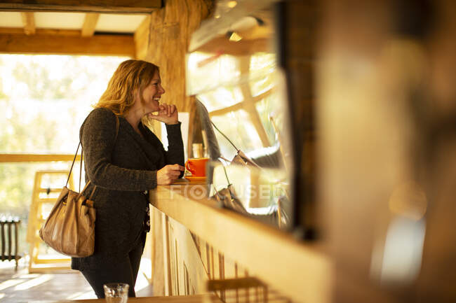 Cliente femenino feliz pidiendo café en el mostrador de café - foto de stock