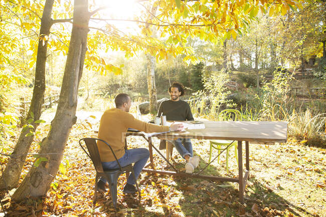 Gli uomini d'affari si riuniscono a tavola nell'idilliaco parco autunnale soleggiato — Foto stock