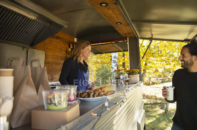 Happy food cart owner talking with customer in park — Stock Photo